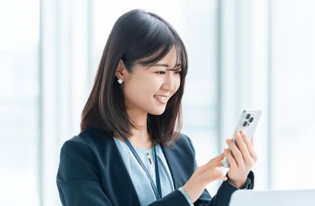 スマホを見ているスーツの女性